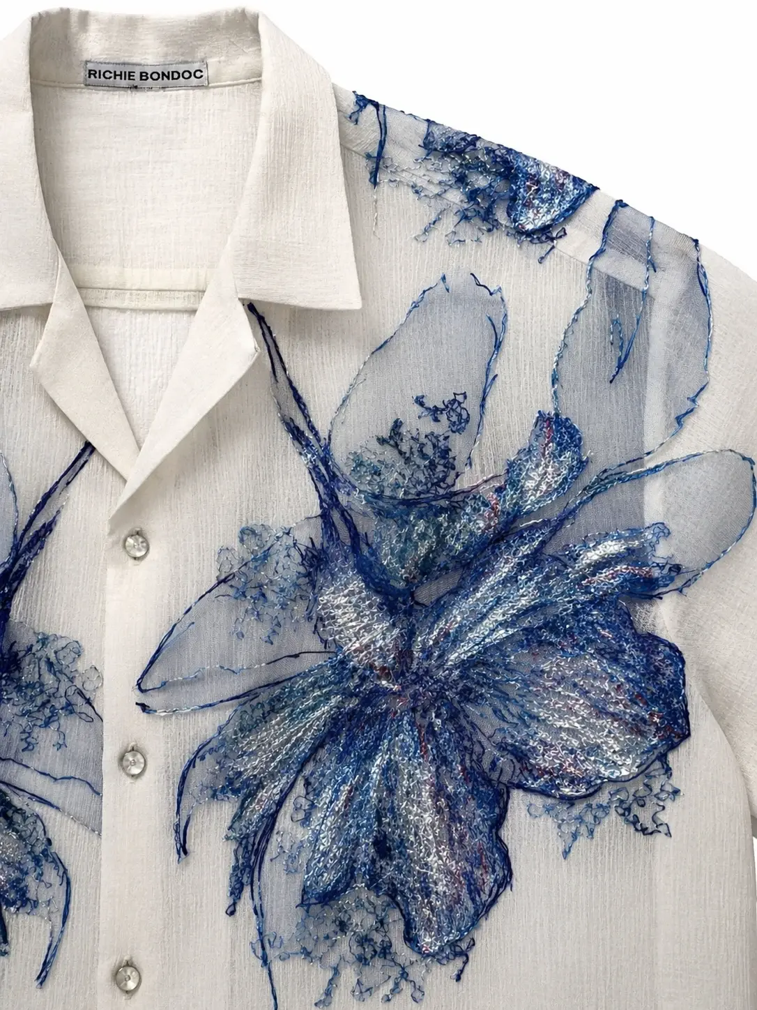Close-up of the modern Barong’s blue floral detailing and visible Richie Bondoc designer label